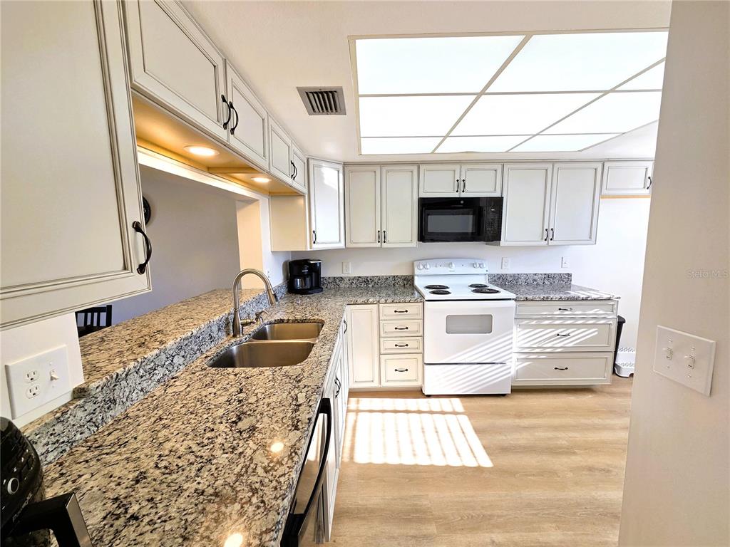401 150th Avenue, Unit 223 Madeira Beach, FL 33708 - Photo 2 of 50 a kitchen with stainless steel appliances kitchen island granite countertop a sink and a stove