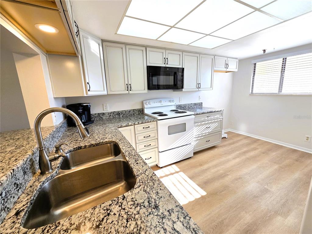 401 150th Avenue, Unit 223 Madeira Beach, FL 33708 - Photo 3 of 50 a kitchen with stainless steel appliances granite countertop a stove and a sink