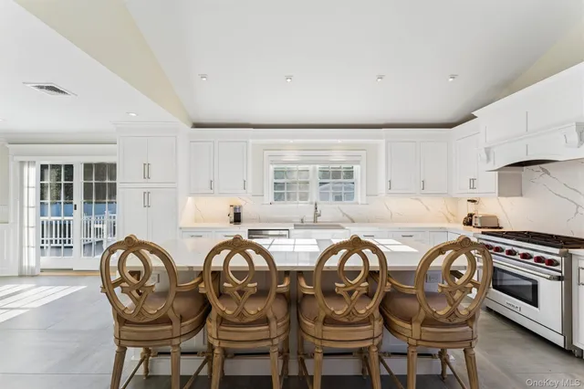 a kitchen with granite countertop a stove a sink dishwasher a dining table and chairs with wooden floor