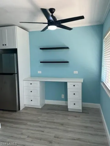 an empty room with wooden floor chandelier fan and windows