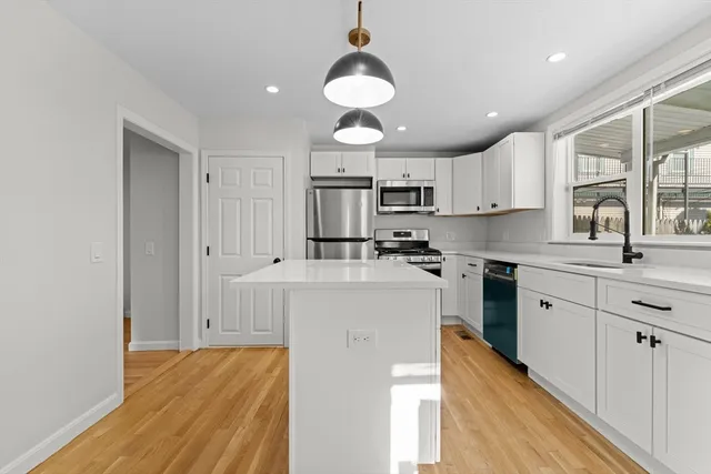 a kitchen with kitchen island granite countertop a sink cabinets and wooden floor