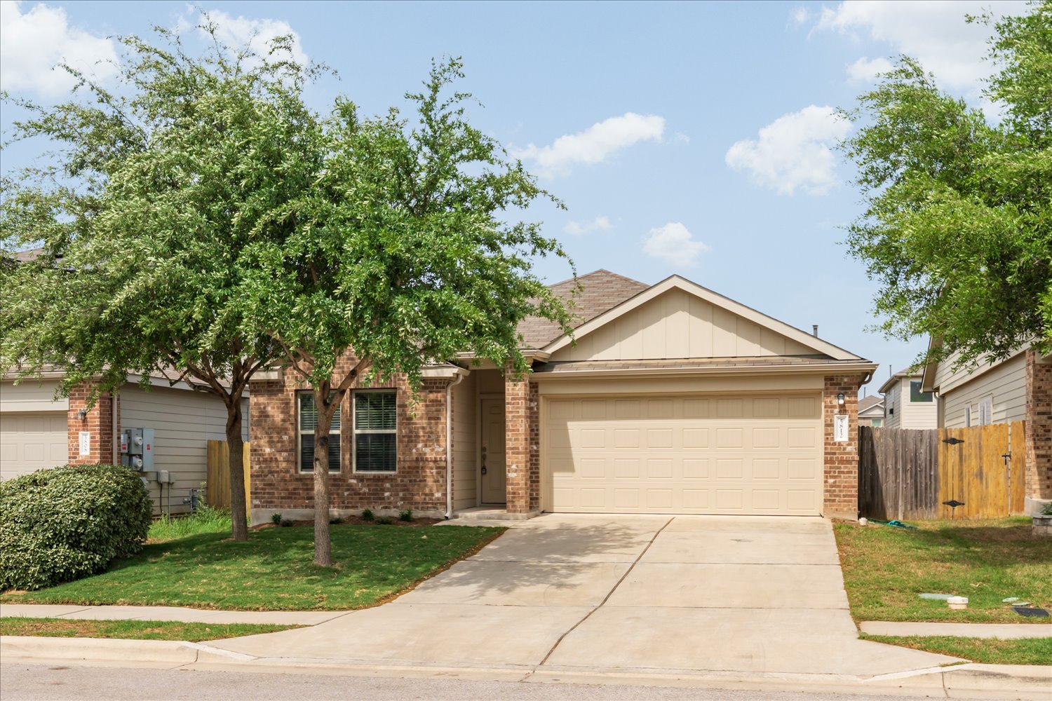 5812 Bell Tower Lane Austin, TX 78747 - Photo 1 of 24 Ranch-style home featuring an attached garage, concrete driveway, board and batten siding, brick siding, and a gate