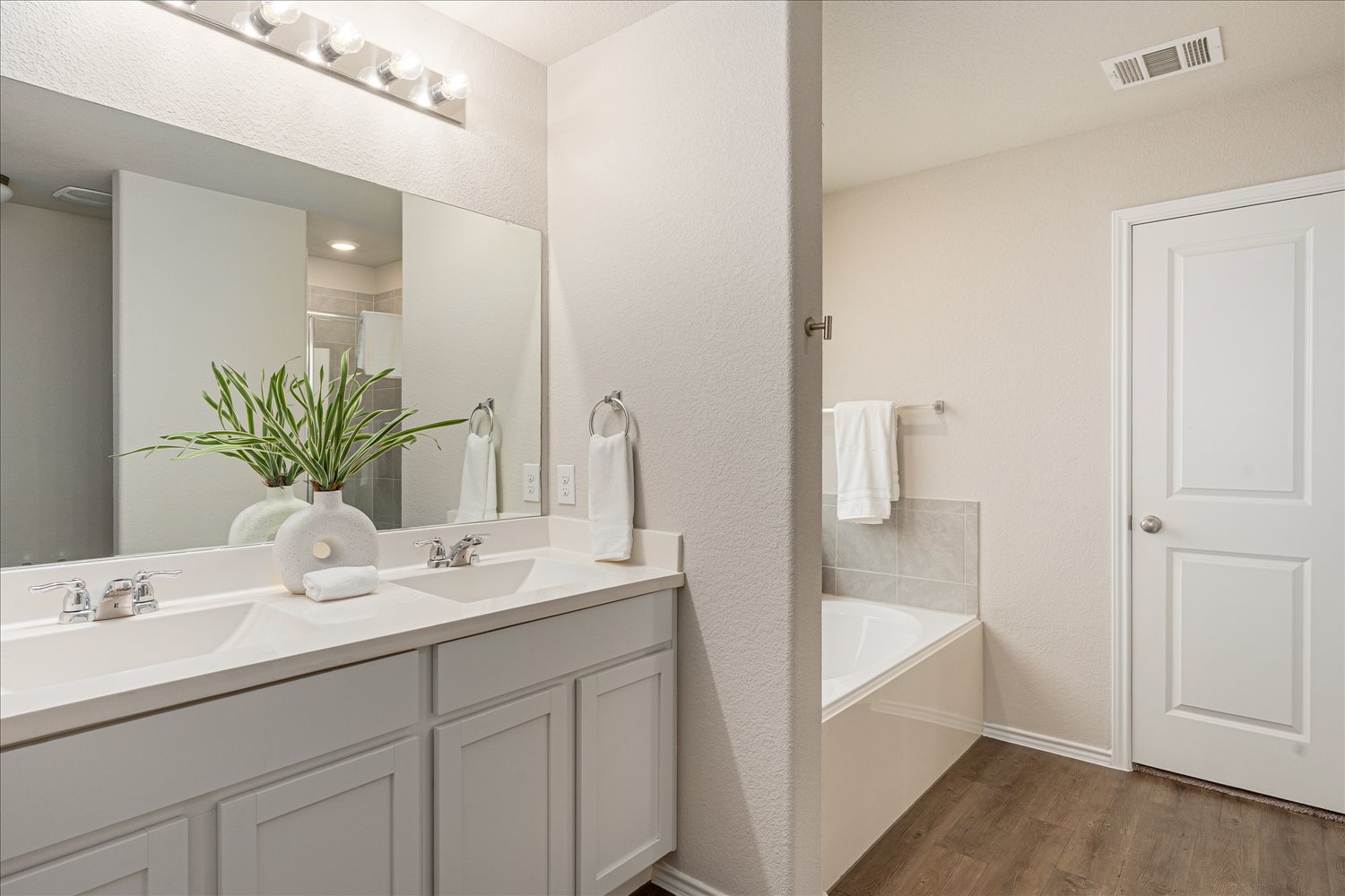 5812 Bell Tower Lane Austin, TX 78747 - Photo 14 of 24 Bathroom with double vanity, dark wood-type flooring, a bath, a textured wall, and a shower stall
