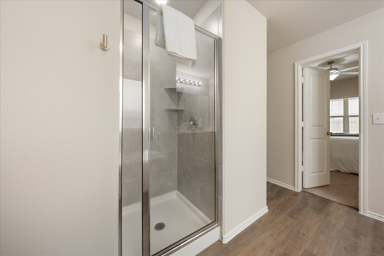 5812 Bell Tower Lane Austin, TX 78747 - Photo 15 of 24 Full bathroom with a ceiling fan, a stall shower, light wood-style floors, and ensuite bath