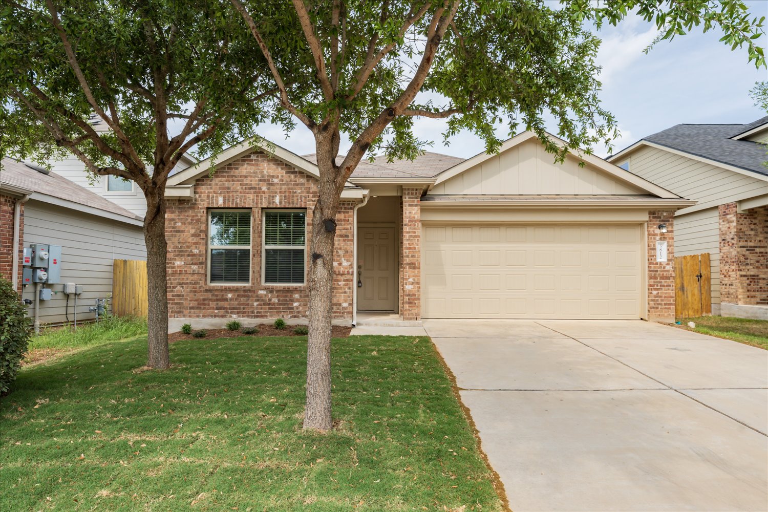 5812 Bell Tower Lane Austin, TX 78747 - Photo 2 of 24 Single story home with board and batten siding, a garage, driveway, brick siding, and a shingled roof