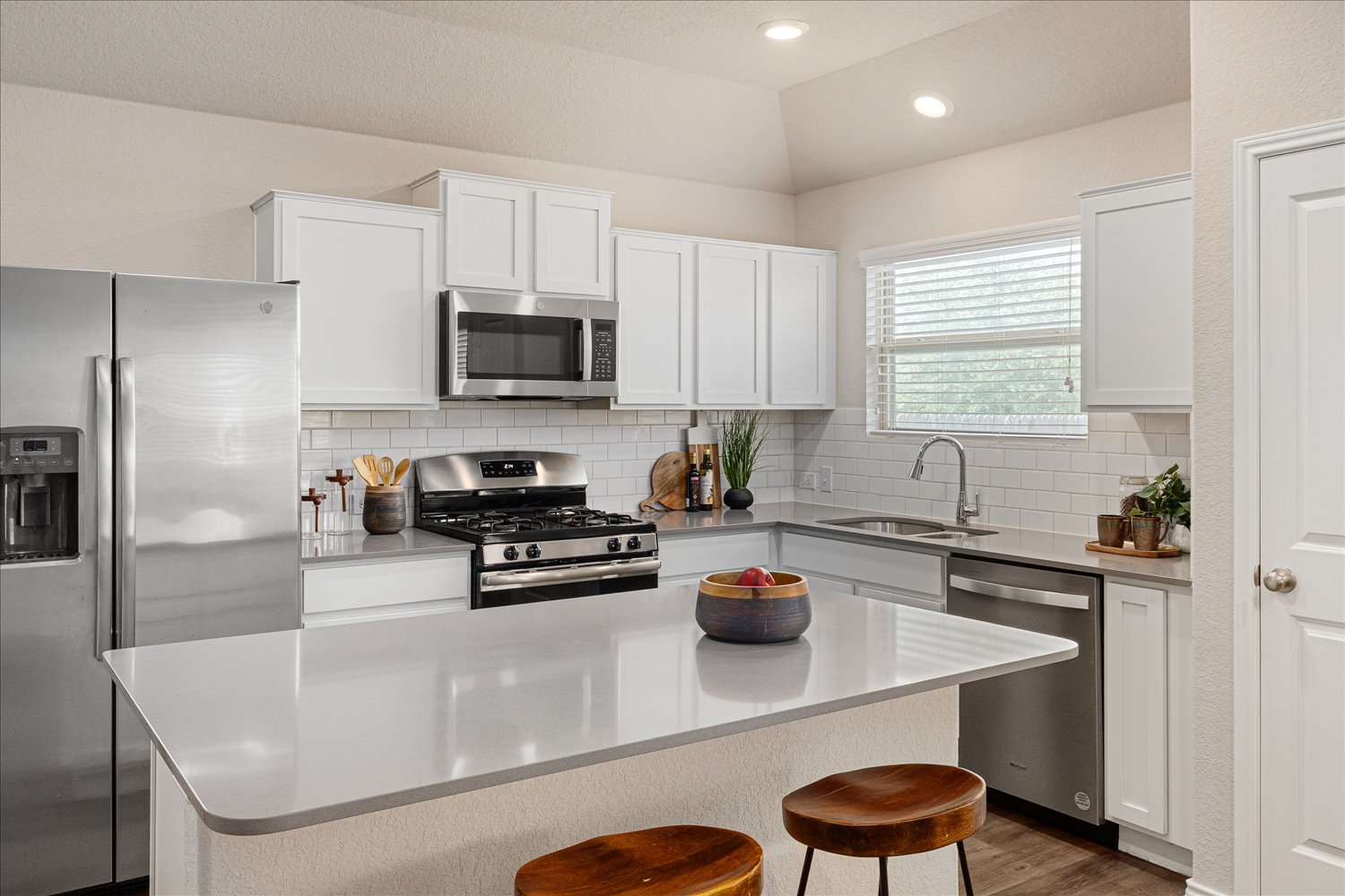 5812 Bell Tower Lane Austin, TX 78747 - Photo 8 of 24 Kitchen with stainless steel appliances, white cabinetry, a kitchen island, dark wood-style floors, and a breakfast bar area