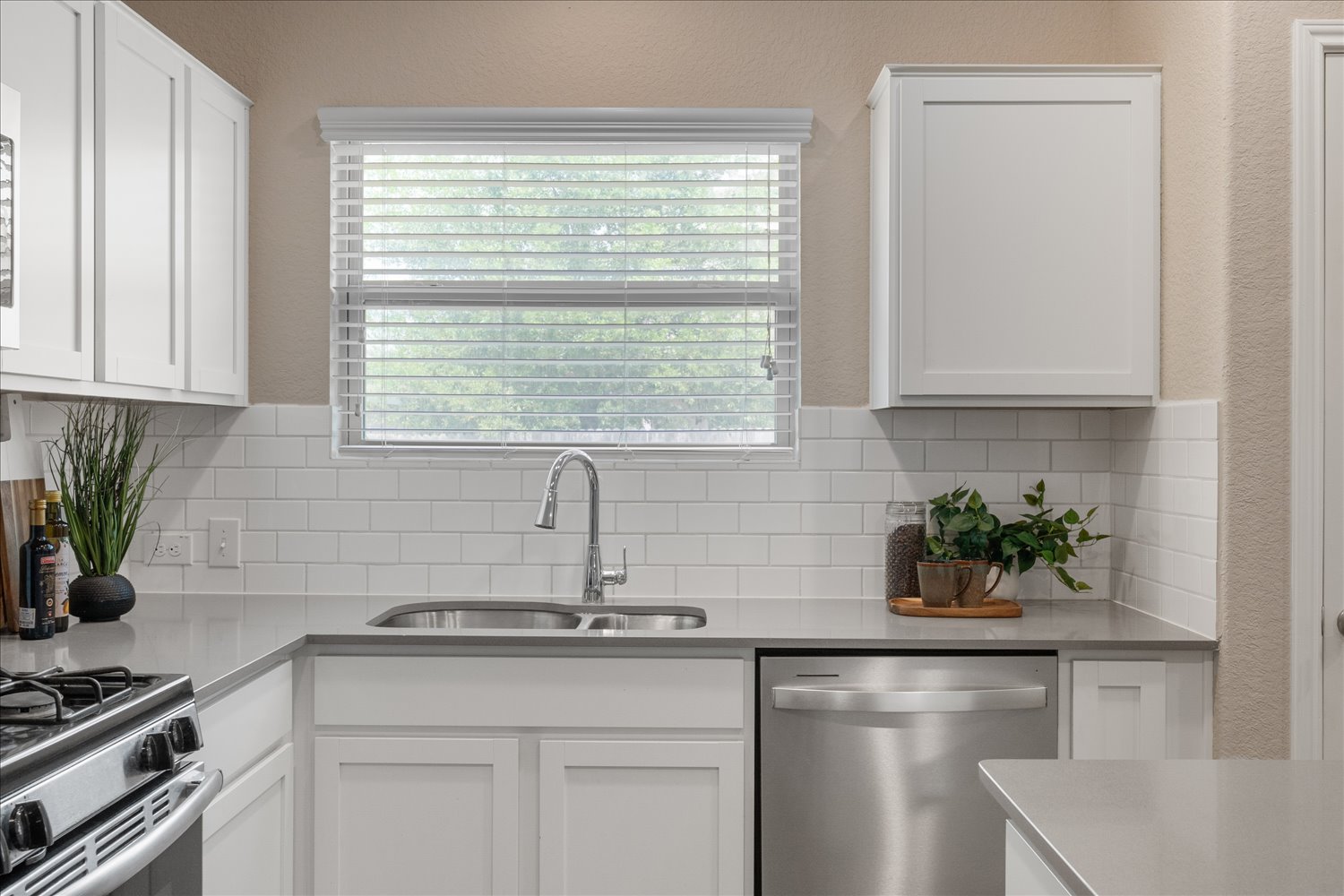 5812 Bell Tower Lane Austin, TX 78747 - Photo 10 of 24 Kitchen with white cabinets, stainless steel appliances, a textured wall, light stone counters, and healthy amount of natural light