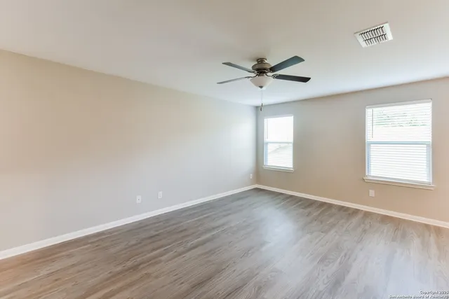 a view of empty room with wooden floor and fan