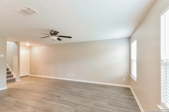 a view of an empty room with wooden floor and a window