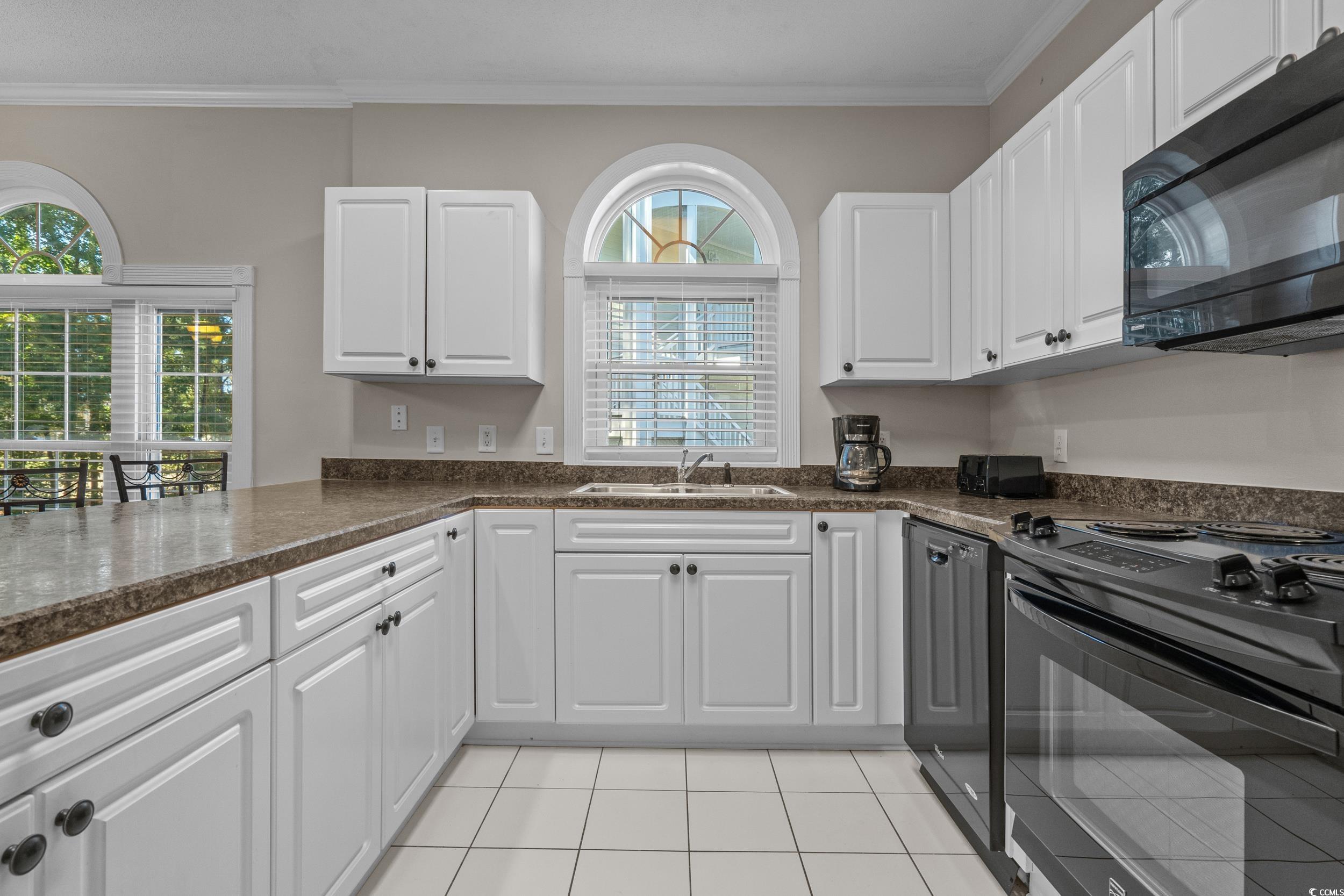 686 Riverwalk Drive, Unit 204 Myrtle Beach, SC 29579 - Photo 11 of 40 Kitchen with black appliances, light tile patterned flooring, white cabinetry, ornamental molding, and dark stone countertops