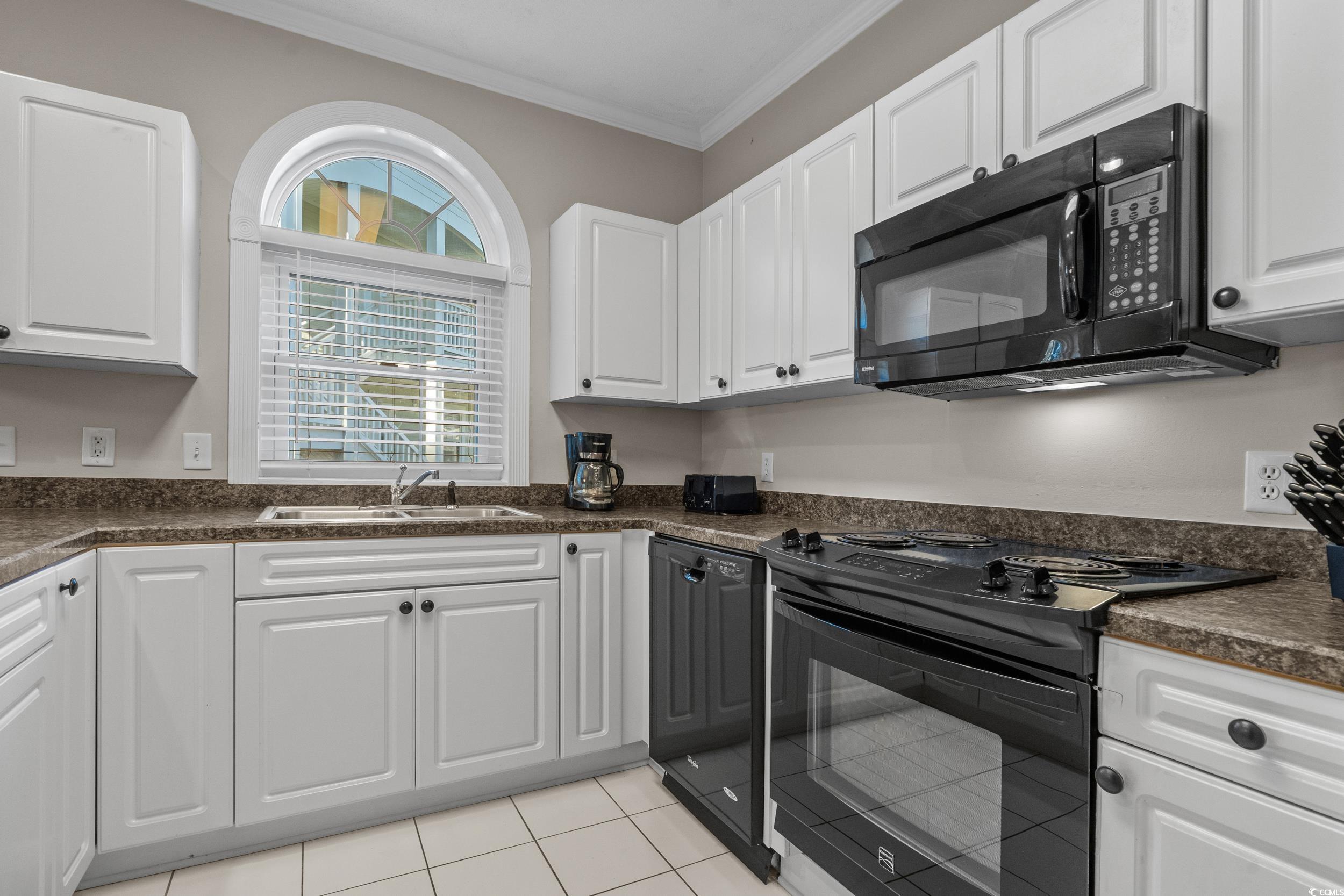 686 Riverwalk Drive, Unit 204 Myrtle Beach, SC 29579 - Photo 12 of 40 Kitchen featuring black appliances, white cabinets, dark countertops, ornamental molding, and light tile patterned floors