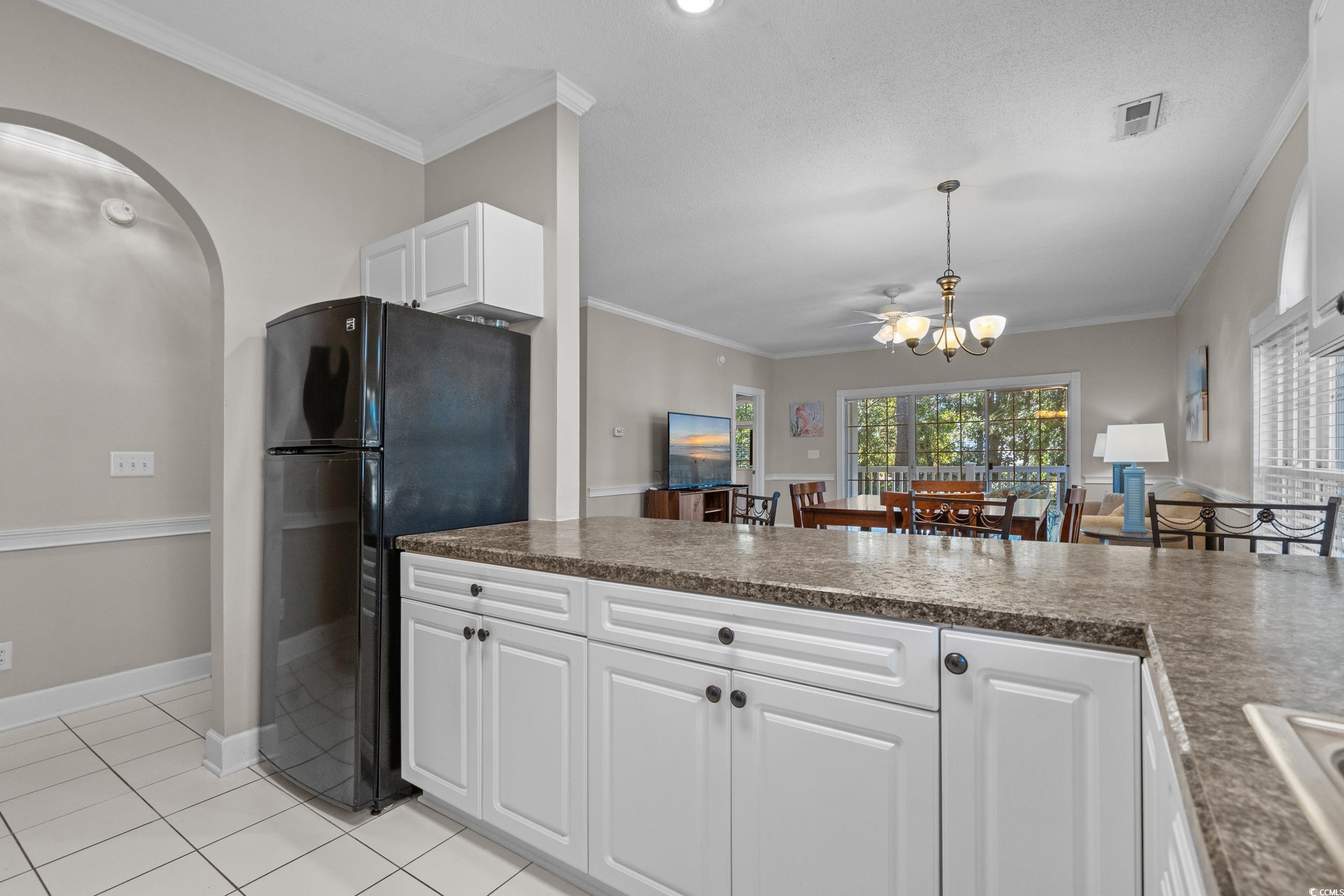 686 Riverwalk Drive, Unit 204 Myrtle Beach, SC 29579 - Photo 14 of 40 Kitchen with crown molding, freestanding refrigerator, white cabinetry, light tile patterned floors, and pendant lighting
