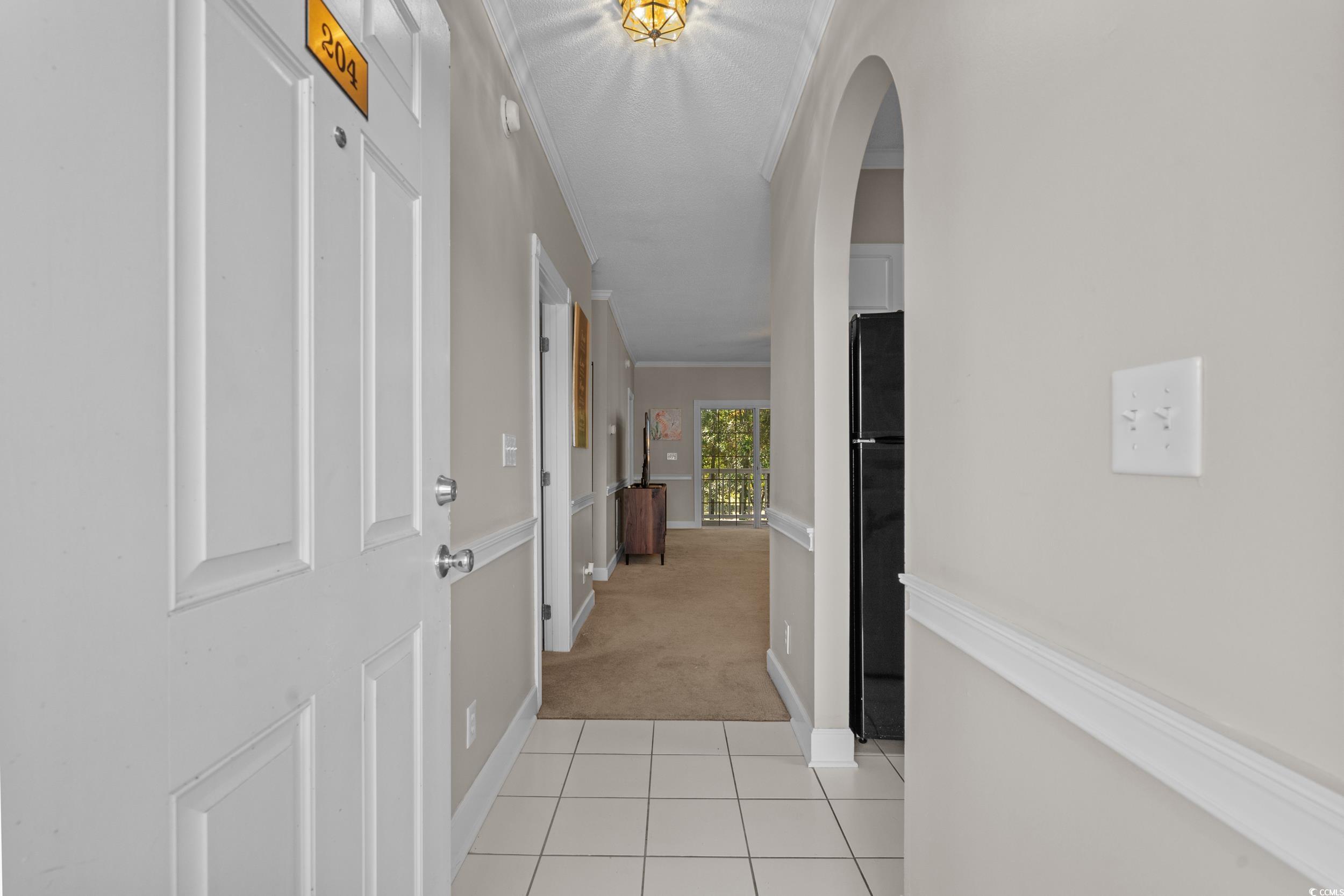 686 Riverwalk Drive, Unit 204 Myrtle Beach, SC 29579 - Photo 3 of 40 Entrance foyer with ornamental molding, light tile patterned floors, arched walkways, and light carpet