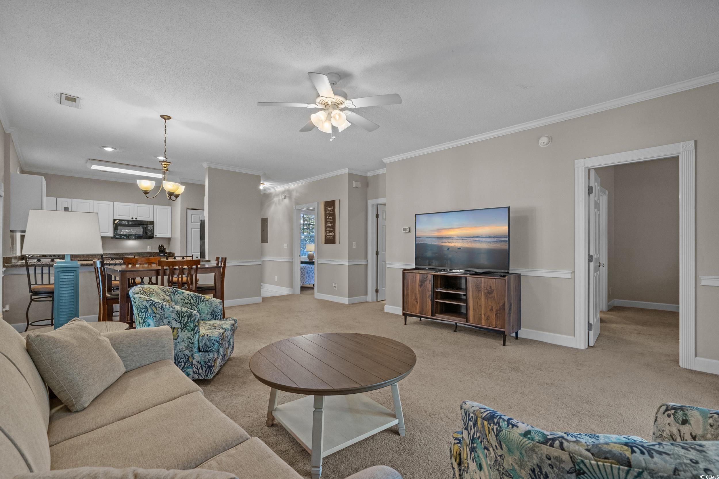 686 Riverwalk Drive, Unit 204 Myrtle Beach, SC 29579 - Photo 10 of 40 Living area with ornamental molding, light colored carpet, a ceiling fan, and a chandelier