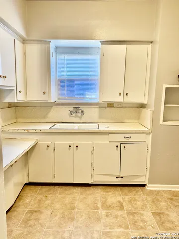 a view of white kitchen with granite countertop cabinets