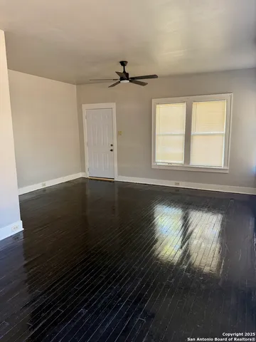 an empty room with wooden floor cabinet and windows
