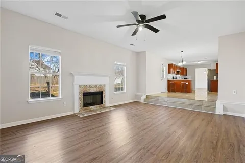 an empty room with wooden floor fireplace and a window