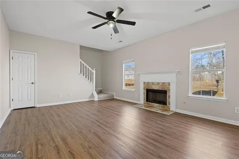 a view of an empty room with wooden floor fireplace and a window