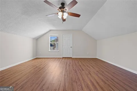 an empty room with wooden floor chandelier fan and windows