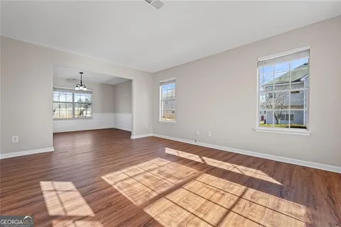a view of an empty room with window and wooden floor