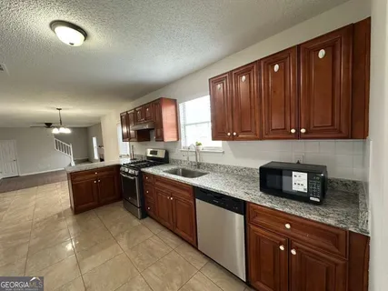 a large kitchen with stainless steel appliances granite countertop wooden cabinets a stove a sink and dishwasher