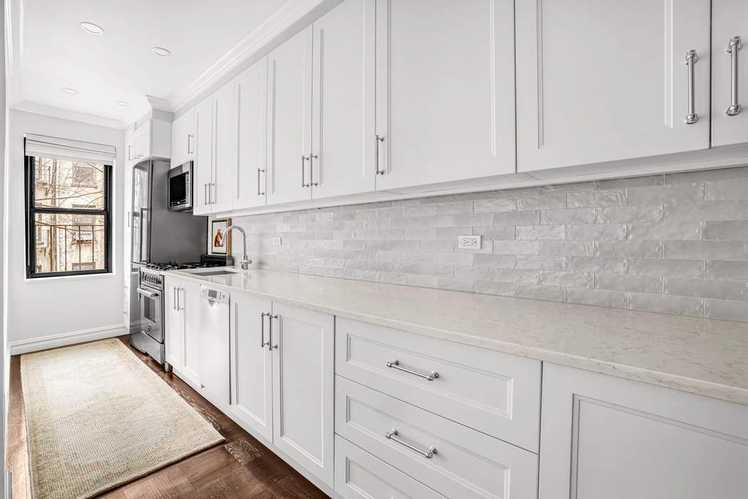 225 East 74th Street, Unit 2M Manhattan, NY 10021 - Photo 5 of 16 a kitchen with white cabinets and white appliances