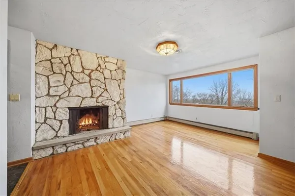 a view of an empty room with a fireplace and wooden floor