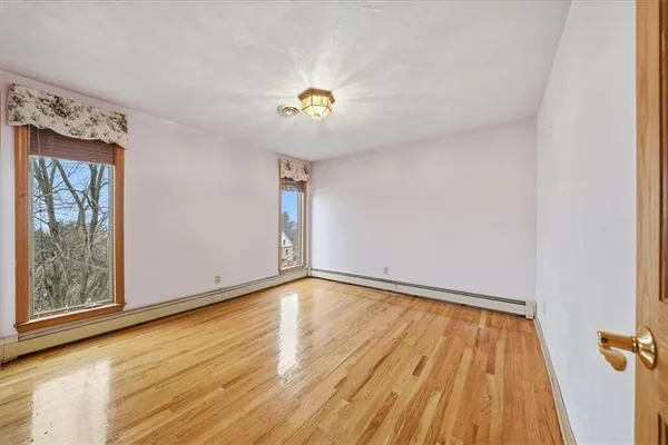 a view of an empty room with a window and wooden floor