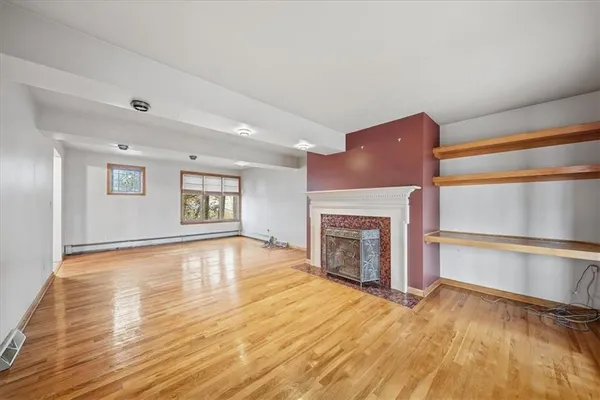 a view of empty room with wooden floor and fireplace