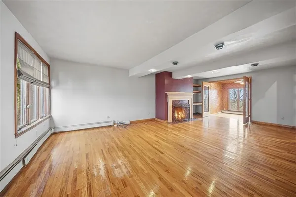 a view of an empty room with wooden floor and a window