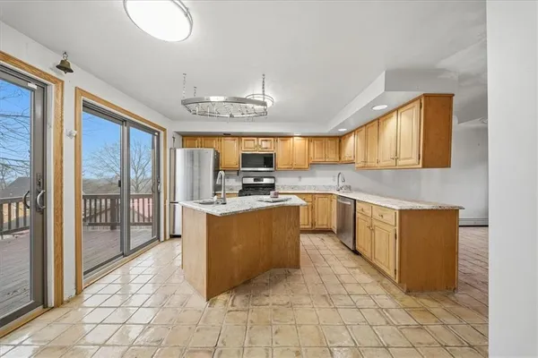 a large kitchen with stainless steel appliances granite countertop a stove a sink dishwasher and a view of living room