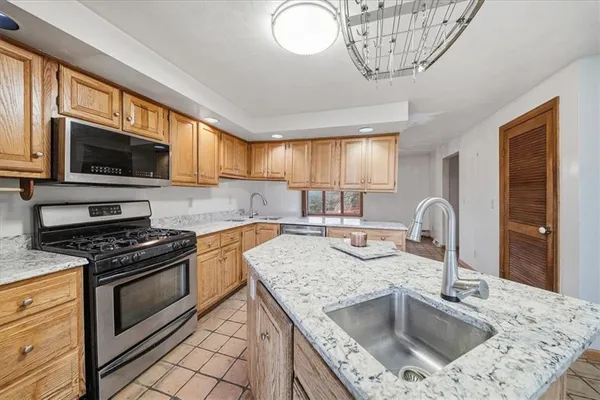 a kitchen with stainless steel appliances granite countertop a sink a stove a microwave a refrigerator cabinets and a dining table