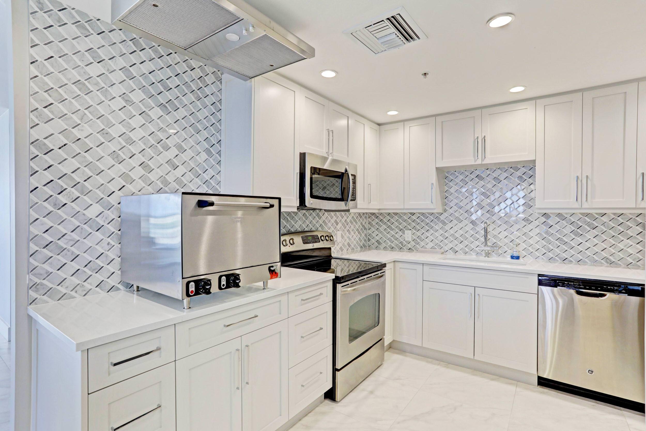 5280 North Ocean Drive, Unit 2F Singer Island, FL 33404 - Photo 51 of 92 a kitchen with granite countertop white cabinets and white appliances