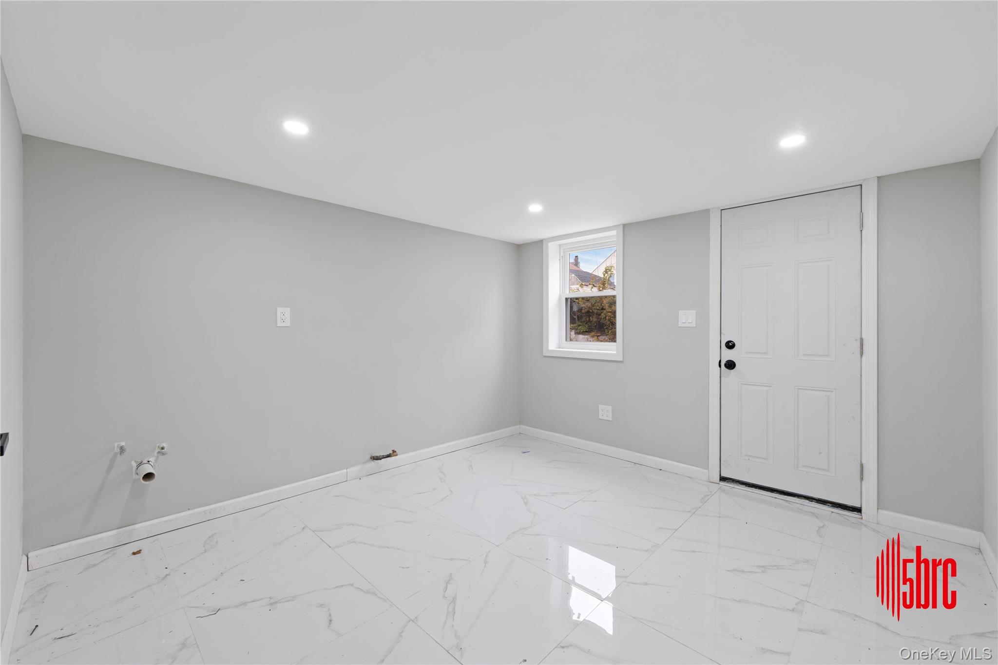217-39 114th Road Queens, NY 11411 - Photo 12 of 23 Below grade area with light marble finish flooring and recessed lighting