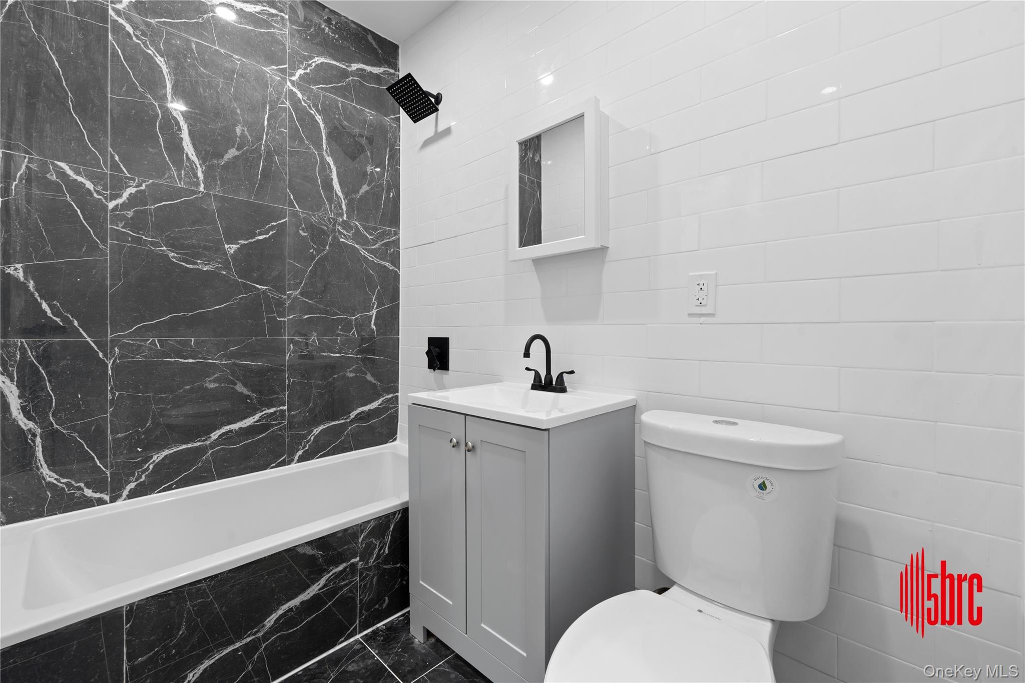 217-39 114th Road Queens, NY 11411 - Photo 18 of 23 Full bathroom featuring tile walls, vanity, a combined bath / shower with marble appearance, and dark marble finish floors