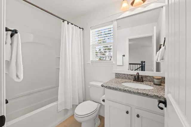 a bathroom with a granite countertop sink a toilet and shower