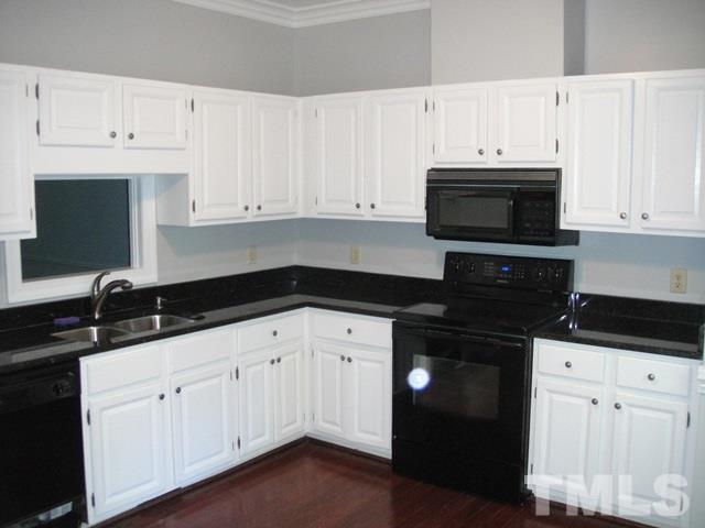 550 Weathergreen Drive Raleigh, NC 27615 - Photo 5 of 25 a kitchen with white cabinets and black appliances