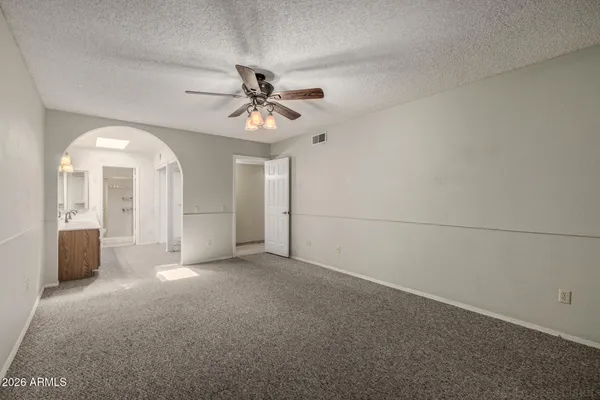 an empty room with chandelier fan and windows