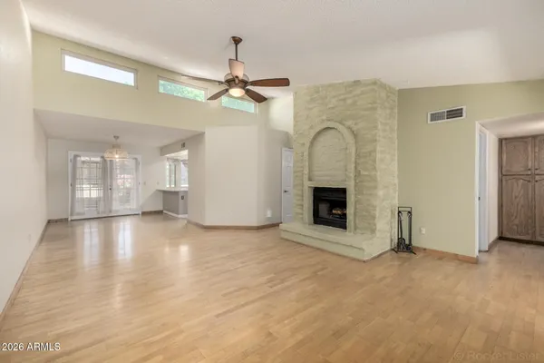 a view of an empty room with chandelier fan and fire place