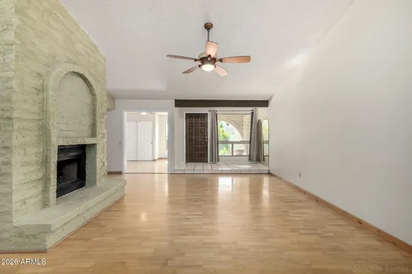 a view of an empty room with chandelier fan and fire place