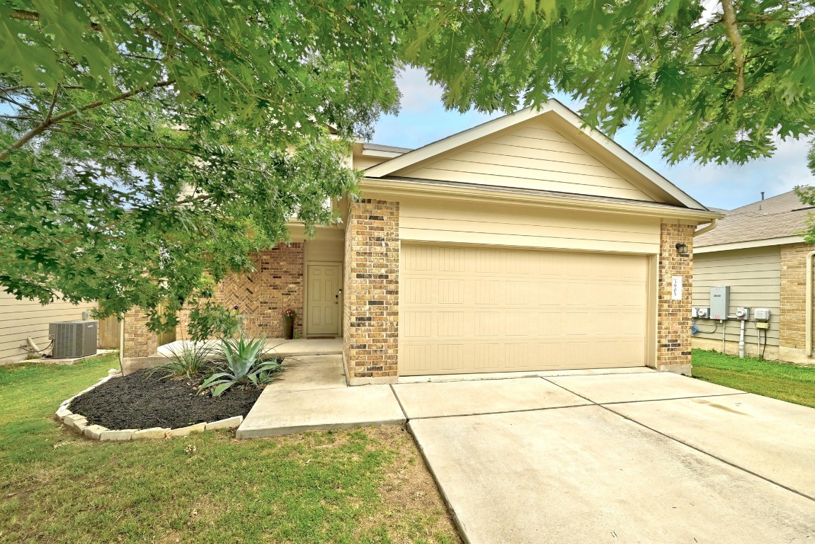 Ranch-style home with brick siding, a garage, driveway, and a front lawn