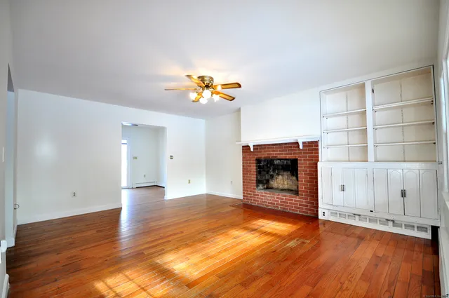 an empty room with a fireplace and wooden floor