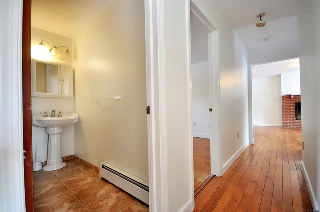 a view of a hallway with wooden floor and a bathroom