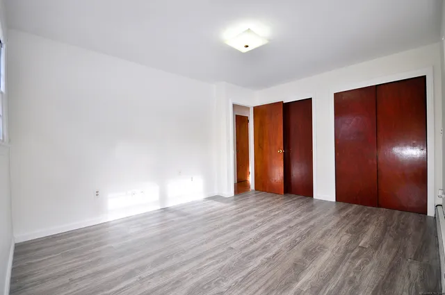 a view of an empty room with wooden floor and window