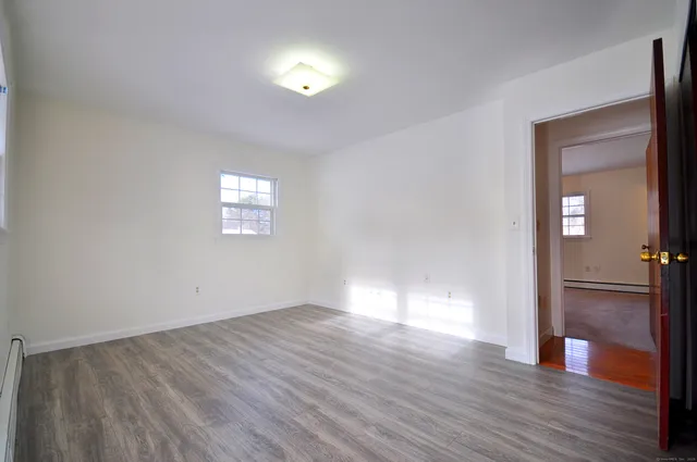 a view of empty room with window and wooden floor