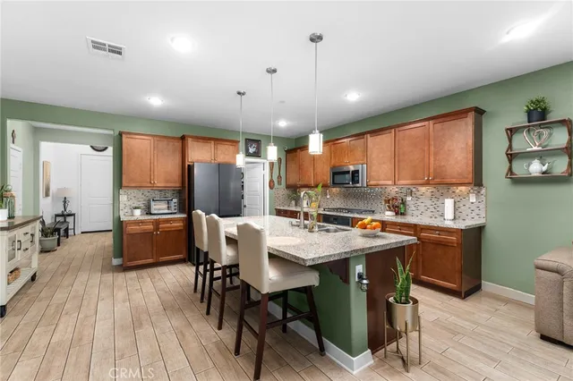 a kitchen with stainless steel appliances a dining table chairs stove refrigerator and cabinets