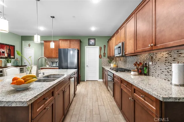 a kitchen with stainless steel appliances granite countertop a sink a stove and a wooden cabinets