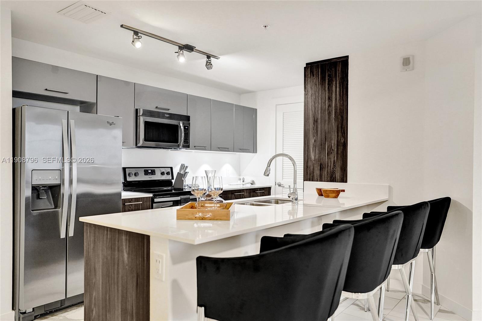 101 East Camino Real, Unit 1025 Boca Raton, FL 33432 - Photo 5 of 12 a kitchen with a sink a microwave a refrigerator and cabinets