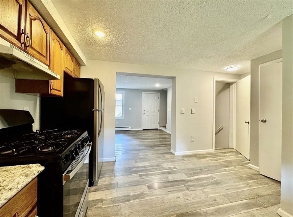 86 Washburn Street, Unit 86 Springfield, MA 01107 - Photo 3 of 8 a kitchen with stainless steel appliances kitchen island granite countertop a stove and a refrigerator