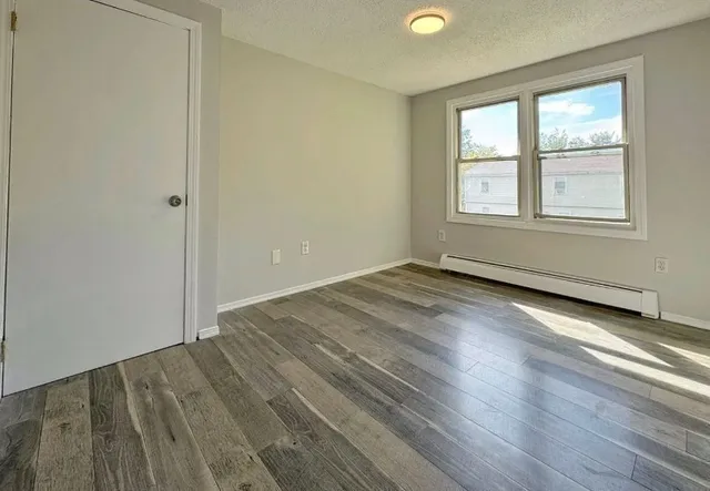 an empty room with wooden floor and windows